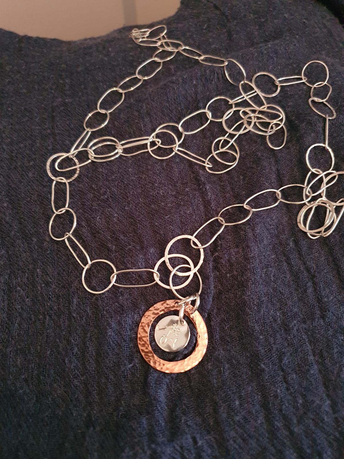 Long, elegant necklace with a 'joy' pendant
