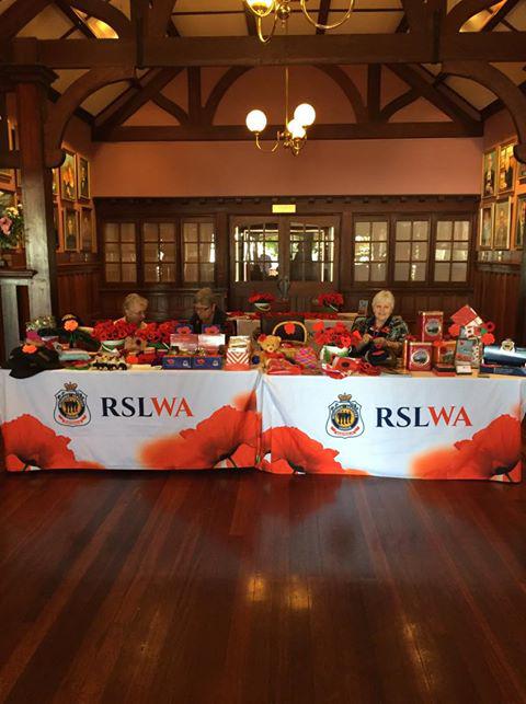 Members of The Poppy Ladies craft knitted poppies at a stall.